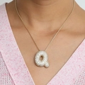 Collier doré avec lettre Q bombée orné de zircons scintillants porté par un mannequin - Collier Q