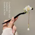 Wooden hair stick with white camellia flower, golden tassel, and green leaf detail - Orchid Tassel Style