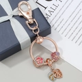 Portachiavi in oro rosa con fiori di ciliegio in cristallo su una scatola regalo blu - Predefinito