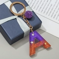 Initial A keychain in purple resin with gold flakes and a purple plush pompom charm - Letter A