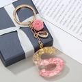 Macro view of resin letter S keychain with pink stones, gold foil, and shell charm - Letter S Style (S)