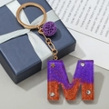 Letter M resin keychain in purple and orange with gold foil and purple pompom charm - M