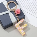 Buchstabe F Schlüsselanhänger aus lila Harz mit bunten Pailletten und Plüschkugel - Buchstabe F