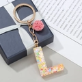 Porte-clés lettre L en résine avec paillettes colorées et un pompon rose en peluche - L