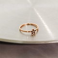 Close-up of rose gold daisy ring with black enamel flower on a brushed metal tray - US 4 / Black