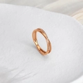 Nahaufnahme des roségoldenen Kreuzrings mit Zirkonia-Besatz auf weißem Federhintergrund - US 5 / Roségold