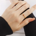 Detailaufnahme eines minimalistischen Goldrings mit rotem Zirkonia am Finger - US 5 / Gold mit roten Strasssteinen