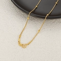 Detail of 24K gold-plated box chain with beads and S-hook clasp on a minimalist display - Box Bead Chain / Gold