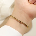 Nahaufnahme eines minimalistischen Armbands mit Goldperlen und schwarzer Kordel - Gold Schwarze Schnur