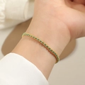 Nahaufnahme eines vergoldeten Armbands mit blauen Edelsteinen am Handgelenk eines Modells - Gold Grüne Schnur