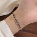 Detail of a minimalist gold bead red string bracelet on wrist with elegant silk background - Steel Color Black String