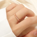 Detailansicht eines roségoldenen Titanrings mit Zirkonia und Pyramidennieten am Finger - US 5 / Roségold