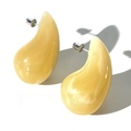 Close-up of yellow teardrop acrylic earrings with silver posts on white background - Beige