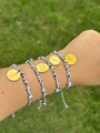 Gros plan de bracelets en corde tressée avec breloques dorées gravées sur un poignet - Collection de Quatre Bracelets