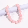 Dettaglio della collana con perle rosa in resina e distanziali dorati su supporto blu - Rosa