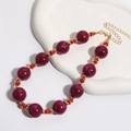 Detail van boho ketting met grote bordeauxrode marmeren kralen en gouden sluiting - KC Goud / Bordeauxrood