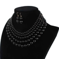 Detail view of a multi-layer black pearl necklace and matching drop earrings on a bust - Black