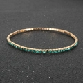 Nahaufnahme des goldene Tennisarmband mit smaragdgrünen Strasssteinen auf dunklem Grund - Grün