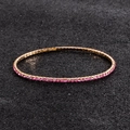 Close-up of pink rhinestones in gold setting on a sparkling elastic tennis bracelet - Pink