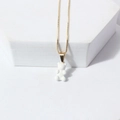 Close-up of a cute white resin bear pendant on a thin gold chain against white background - White