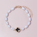 Elegant pearl bracelet for women featuring a black clover charm and gold accents - Black