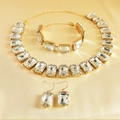 Detailed close-up of golden rhinestone jewelry set with emerald-cut crystals on silk - White