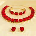 Detailed macro view of red rhinestone necklace, bracelet, and earrings set on gold fabric - Red