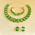 Detailed close-up of emerald green rhinestone jewelry set with gold plated finish - Green