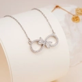 Silver infinity bow necklace with micro-paved zircons on a white jewelry stand - Silver Infinity White Zirconia Style (2548)