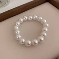 Macro view of 12mm white pearls on a stretch bracelet with high glossy finish - 12mm Pearl / Electroplating