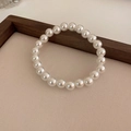 Detailed top view of a classic white pearl stretch bracelet on a textured fabric surface - 8mm Pearl / Electroplating