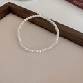 Detailed view of elegant white round pearls with high luster on a beige display pad - 4mm Pearl / Electroplating