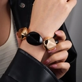 Detail eines klobigen gold-schwarzen elastischen Armbands mit schwarzer Lederjacke - Schwarz Gold Elastisches Armband Glänzende Perlen (NK27340)
