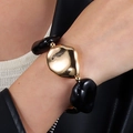 Detail eines klobigen Gold- und schwarzen Harzarmbands über einem weißen Strickärmel - Schwarz Gold Organische Form Armband (NK27350)