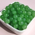 Close-up of polished green glass jade-like round beads with pre-drilled holes for DIY jewelry - 8mm / Apple Green