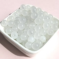 Macro detail of translucent white glass beads with center holes in a ceramic bowl - 8mm / White