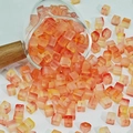 Vue rapprochée de perles en verre de 7mm en dégradé sortant d'un récipient en verre - 7mm / Dégradé Orange Rouge Jaune Pâle