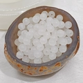 Close-up of translucent white chalcedony glass beads in a natural stone bowl for DIY - 4mm / White