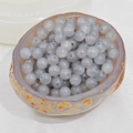 Close-up of translucent grey chalcedony round beads in a stone bowl for DIY jewelry - 10mm / Light Gray