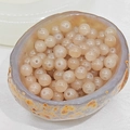 Detail view of semi-transparent beige agate round beads in a natural stone bowl - 10mm / Khaki