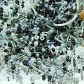 Macro shot of mixed black and silver glass seed beads pouring onto a reflective surface - Black (M754)