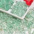 Macro shot of light green cylinder glass beads with gold texture in a ceramic tray - J76 Brushed Transparent Bamboo Cyan