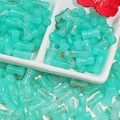 Close-up of bamboo-shaped glass beads with gold texture in a white ceramic dish - J62 Brushed Jade Style Bamboo Teal