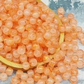 Dettaglio macro di perle in vetro pesca con motivo craquelé e intarsio in foglia d'oro - Arancione