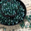 Macro shot of 10mm turquoise cracked glass beads for DIY jewelry making on calligraphy paper - Two-Tone Crackle Style (H204) / 8mm / Light Green
