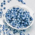 Macro detail of 10mm blue and white cracked glass beads on a shell-shaped tray - Blue (H3)