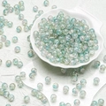 Detailed macro view of 10mm crackle glass beads in a white shell-shaped porcelain tray - Transparent Green Style(H124) / 10mm