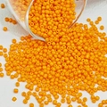 Macro-detail van feloranje ronde glazen kralen die uit een glazen container worden gegoten - Oranje