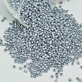Detailopname van zilveren glaskralen die uit een pot vallen voor DIY-sieraden maken - Zilver