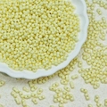 Pale yellow 3x6mm two-hole peanut glass beads displayed on a white floral plate - Pale Yellow